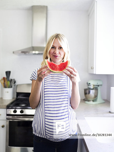Schwangere Frau hält eine Scheibe Wassermelone