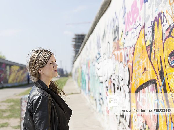 Woman looking at graffiti on Berlin Wall  Berlin  Germany