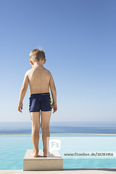 Junge steht am Rande des Schwimmbads