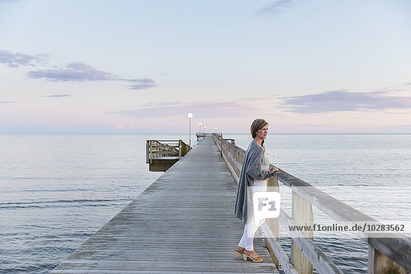 Woman on pier looking at sea