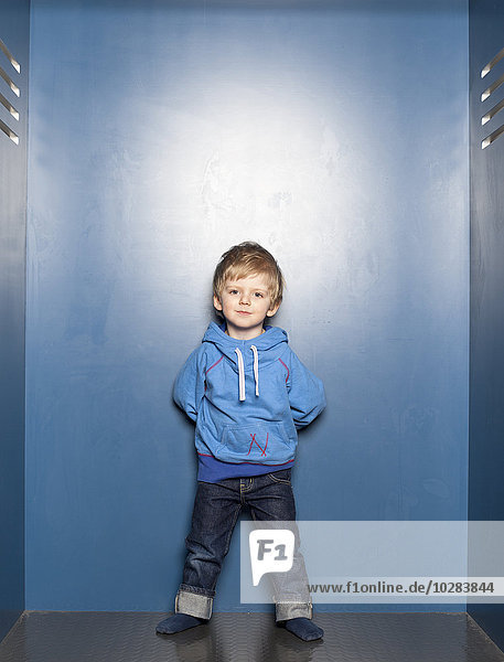 Junge vor blauer Wand stehend