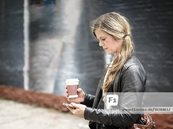 Woman with coffee using cellphone