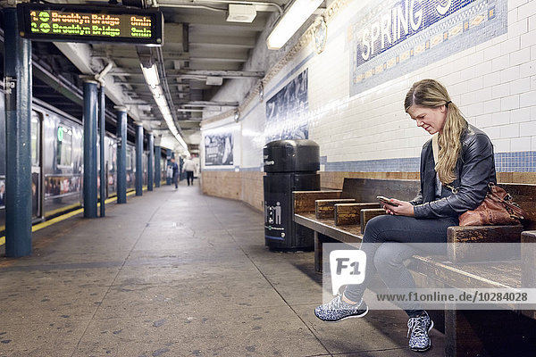 Frau benutzt Mobiltelefon auf einem Bahnhof. New York City  USA