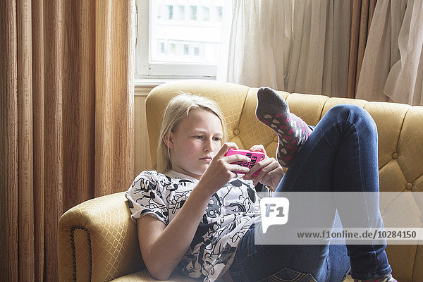 Mädchen auf Sofa mit Handy