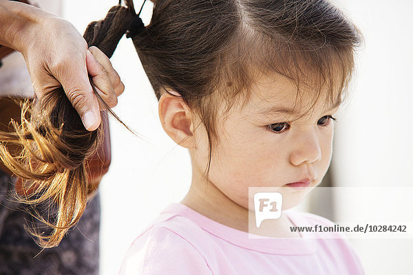 Mother making daughter ponytail