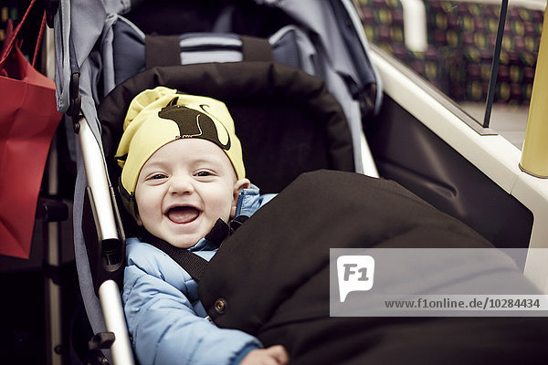Porträt eines lachenden Jungen im Kinderwagen