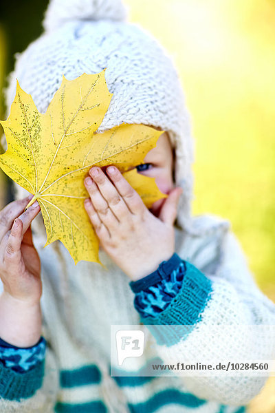 Porträt eines Kleinkindes mit Herbstblatt