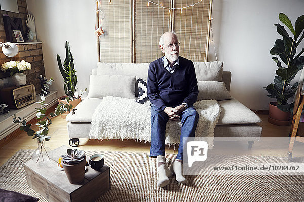 Älterer Mann sitzt im Wohnzimmer