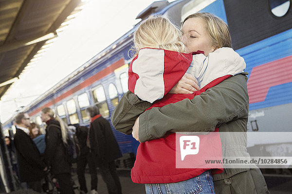 Mother hugging daughter on train station