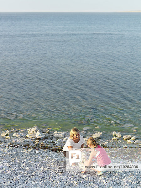 Mother with daughter stacking stones on beach