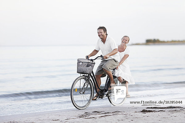 Couple cycling on beach
