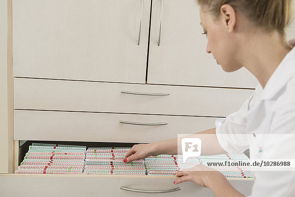 Female doctor searching for medical records in a drawer  Munich  Bavaria  Germany