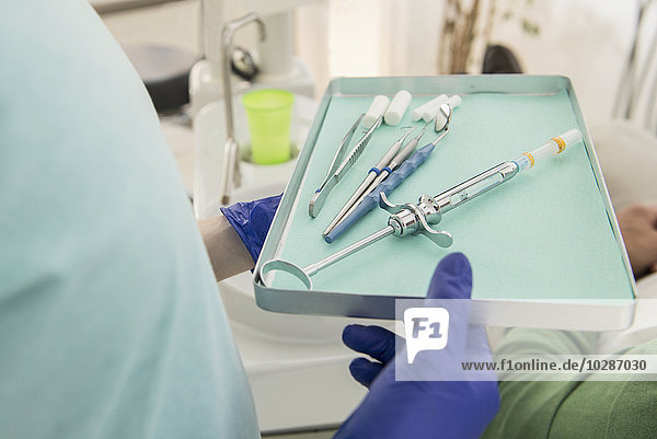 Zahnmedizinische Fachangestellte hält ein Tablett mit zahnmedizinischen Instrumenten in der Zahnklinik  München  Bayern  Deutschland