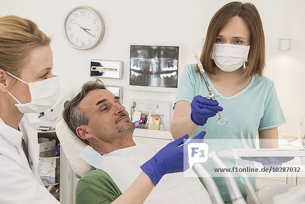 Female dentist examining patient with dental assistant  Munich  Bavaria  Germany