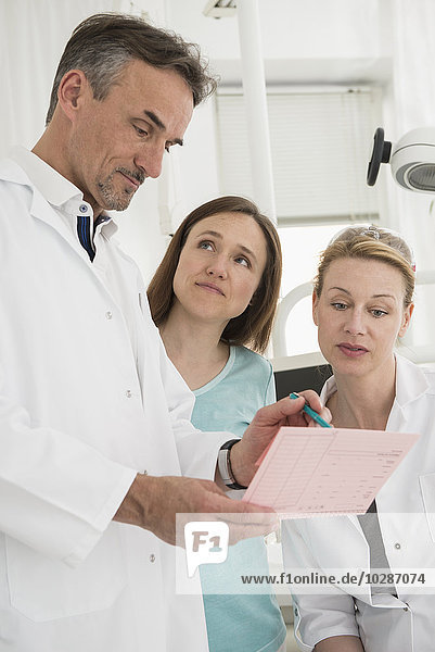 Dentists discussing the index card of a patient with dental assistant  Munich  Bavaria  Germany