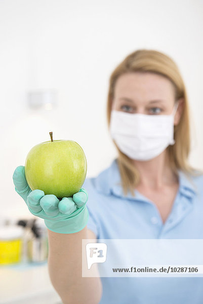 Laboratory technician holding a green apple  Munich  Bavaria  Germany