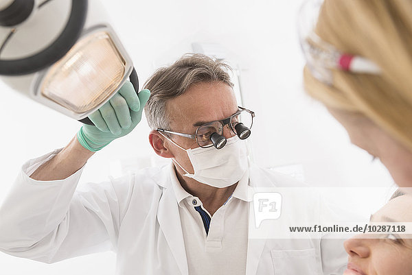 Nahaufnahme eines Zahnarztes  der einen Patienten mit Lupen auf einer Brille untersucht  München  Bayern  Deutschland