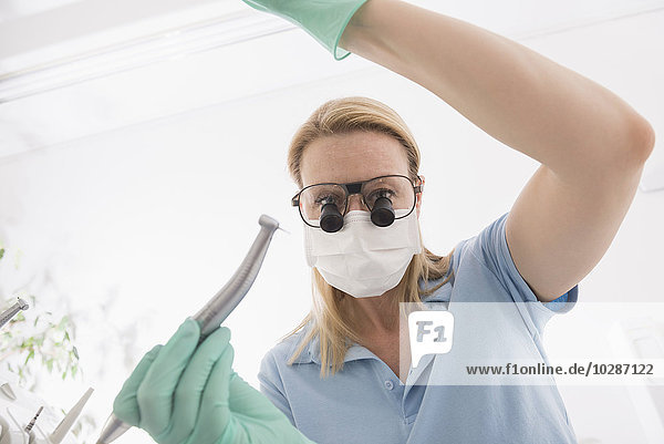 Close-up of female dentist holding dental drill with magnifiers on eyeglasses  Munich  Bavaria  Germany