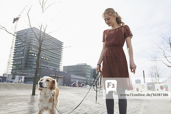 Young woman standing in the playground with her dog  Munich  Bavaria  Germany