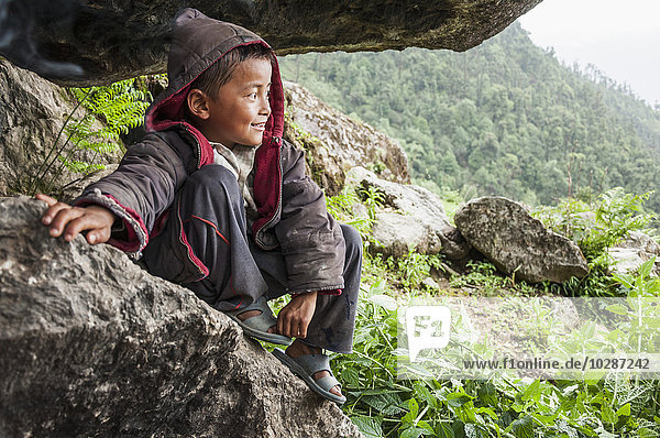 Boy sitting on rock and looking at mountain view  Nepal
