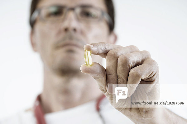 Male doctor showing a capsule of dietary supplement Bavaria Germany