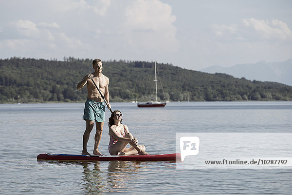Mature couple paddleboarding in the lake  Bavaria  Germany