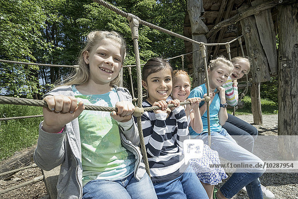 Girls sitting on rope bridge in playground  Munich  Bavaria  Germany