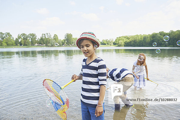 Girl with her friends catching soap bubbles with fishing nets  Bavaria  Germany