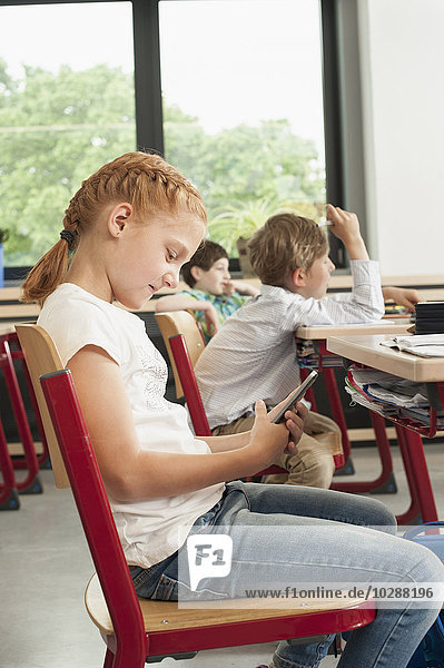 Side profile of a schoolgirl using a smart phone in classroom  Munich  Bavaria  Germany