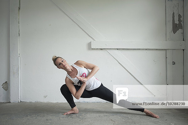 Mid adult woman practicing parighasana pose in yoga studio  Munich  Bavaria  Germany