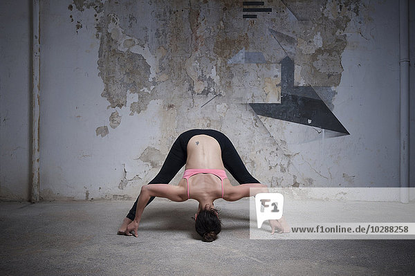Mittlere erwachsene Frau beim Üben der Prasarita Padottanasana-Pose im Yogastudio  München  Bayern  Deutschland
