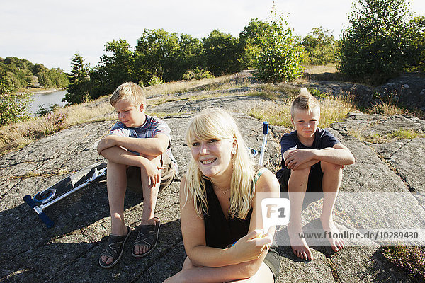 Sweden Blekinge Karlskrona Mother sitting on rock with sons (6-7 14-15)