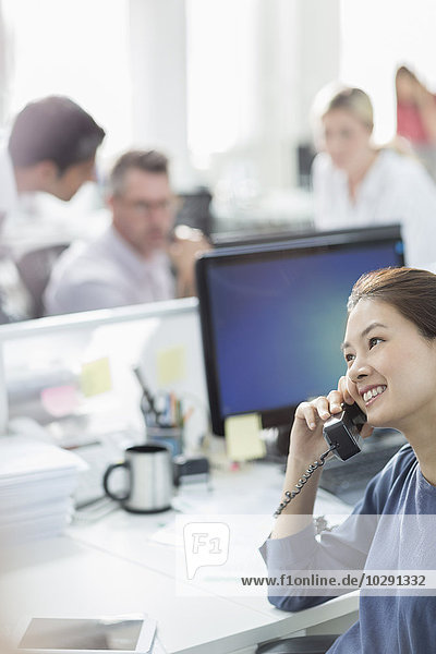 Smiling businesswoman talking on telephone at desk in office