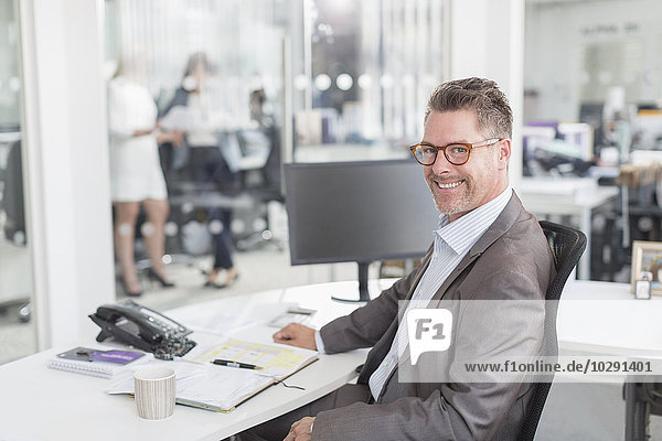 Porträt selbstbewusster Geschäftsmann am Schreibtisch im Büro