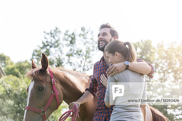 Lächelndes Paar umarmt das Pferd