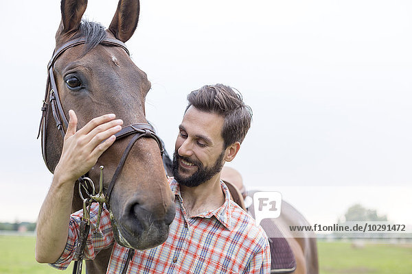 Lächelnder Mann umarmt Pferd