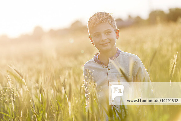 Portrait lächelnder Junge im sonnigen ländlichen Weizenfeld