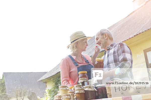 Liebevolles Seniorenpaar  das Honig auf dem Bauernmarkt verkauft.