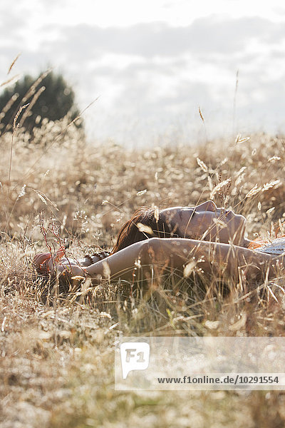 Gelassene Frau schläft im sonnigen ländlichen Feld