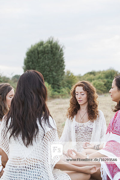 Boho Frauen meditieren im Kreis im ländlichen Raum