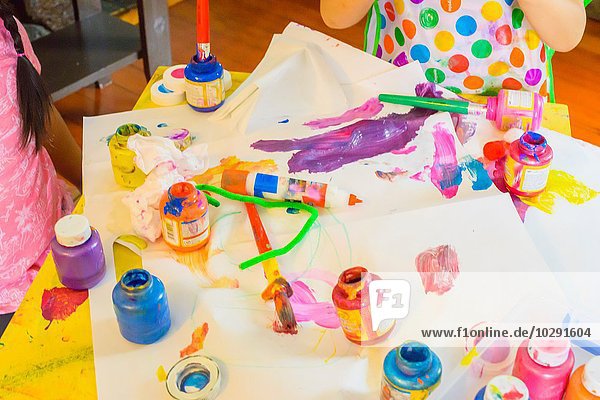Zwei junge Mädchen  die am Tisch sitzen  Kunst machen  Farbe benutzen  sich auf Kunst konzentrieren