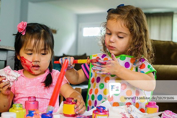 Zwei junge Mädchen  die am Tisch sitzen  Kunst machen  mit Farbe.
