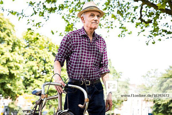 Senior Mann mit Fahrrad im Park  Hackney  London