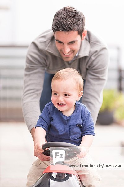 Father and and young son playing together  son riding toy car