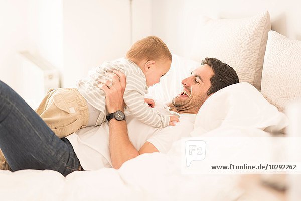 Father and young son relaxing together on bed  laughing