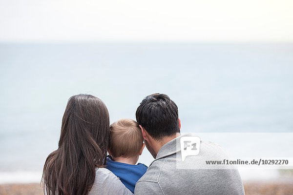 Junge Familie mit Blick aufs Meer  Rückansicht