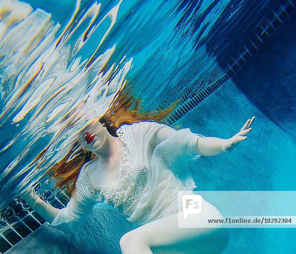 Junge Frau unter Wasser  trägt dünnes weißes Hemd