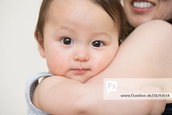 Close up portrait of cute baby boy in mature mothers arms