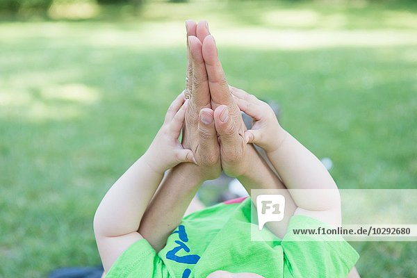 Schnappschuss von Müttern und Babysöhnen Hände zusammen im Park
