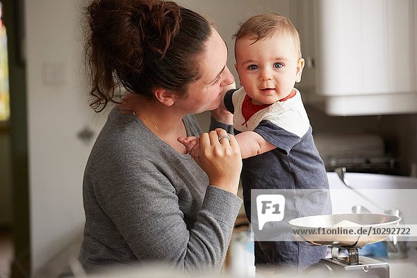 Mother holding baby boy on kitchen counter